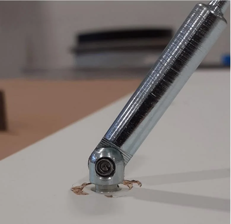 Scharnierdrevel met de koppeling nog zichtbaar boven het paneel